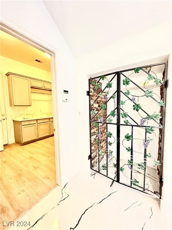 hall with lofted ceiling and light hardwood / wood-style flooring