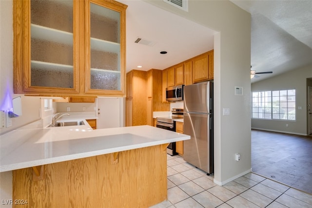 kitchen featuring kitchen peninsula, vaulted ceiling, light tile patterned flooring, appliances with stainless steel finishes, and ceiling fan