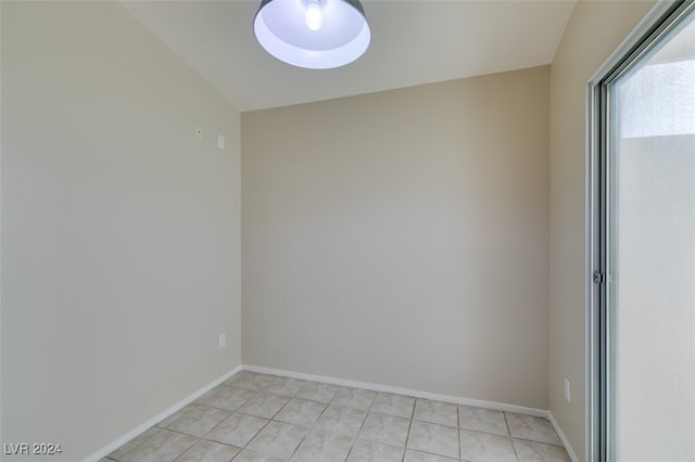 tiled spare room featuring vaulted ceiling