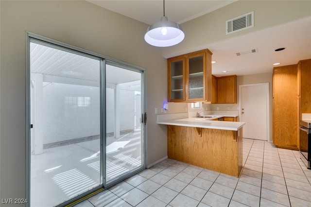 kitchen with sink, kitchen peninsula, a breakfast bar area, pendant lighting, and light tile patterned floors