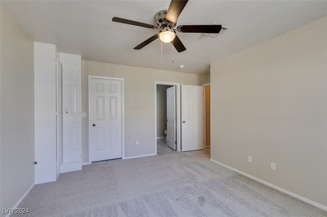 unfurnished bedroom with ceiling fan, light carpet, and ensuite bath