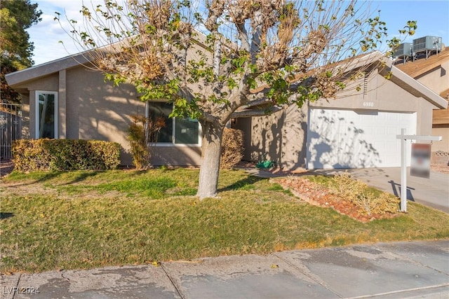 view of front of home featuring central AC, a garage, and a front lawn