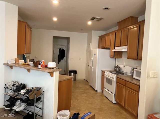 kitchen featuring a kitchen breakfast bar, kitchen peninsula, and white appliances