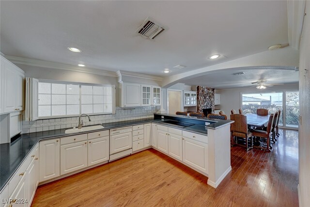 kitchen featuring kitchen peninsula, sink, dishwasher, light hardwood / wood-style floors, and white cabinetry