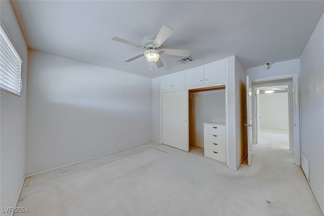 unfurnished bedroom with ceiling fan, light colored carpet, and a closet