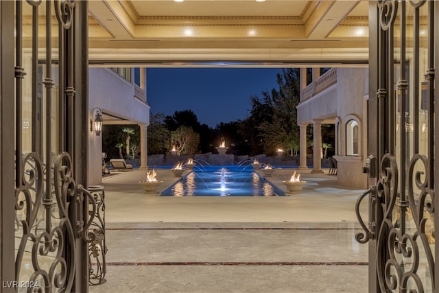 pool at twilight featuring a hot tub, a patio area, and pool water feature