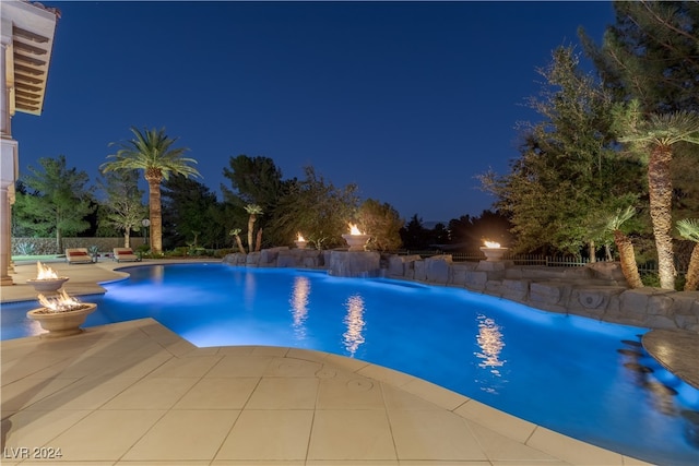 pool at twilight with a patio area and pool water feature