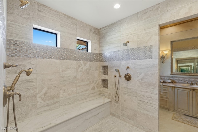 bathroom with a tile shower, tile walls, and vanity