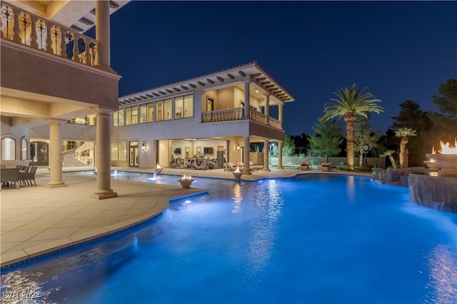 pool at twilight featuring pool water feature and a patio area