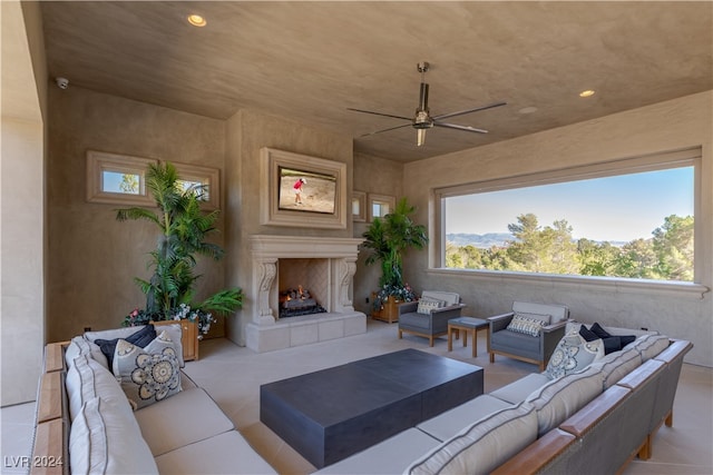 tiled living room with a tiled fireplace and ceiling fan