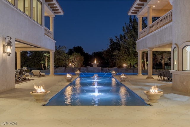 pool at twilight featuring a patio and pool water feature