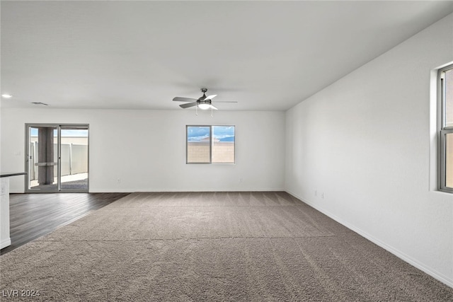 unfurnished room featuring a healthy amount of sunlight, dark wood-type flooring, and ceiling fan