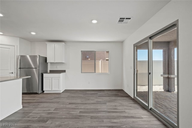 kitchen with hardwood / wood-style flooring, stainless steel refrigerator, and white cabinets