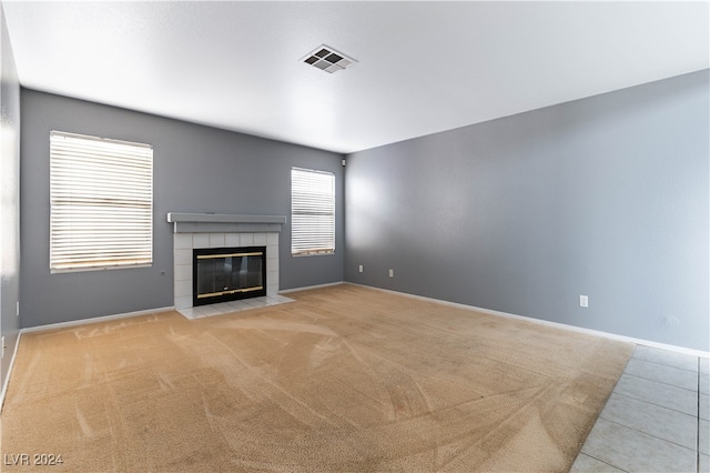 unfurnished living room featuring a fireplace, light carpet, and a healthy amount of sunlight