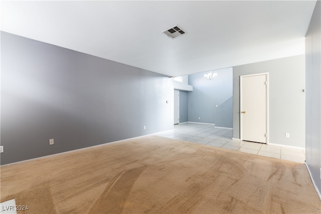 spare room with a notable chandelier and light carpet