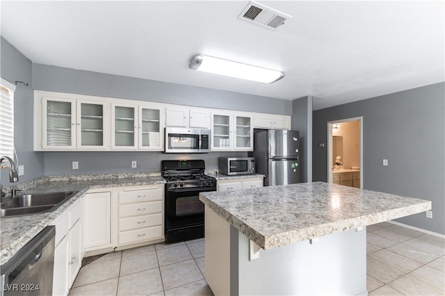 kitchen featuring white cabinets, sink, light tile patterned floors, appliances with stainless steel finishes, and a kitchen island