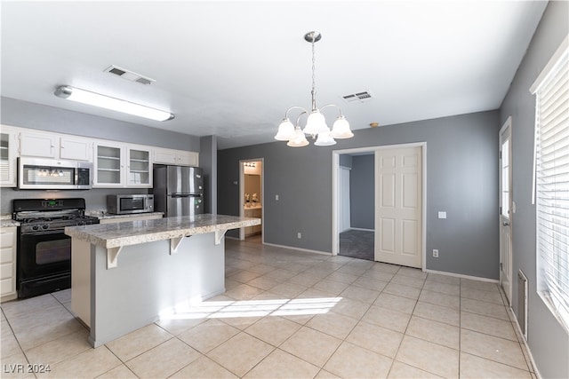 kitchen featuring white cabinets, pendant lighting, a kitchen bar, and stainless steel appliances