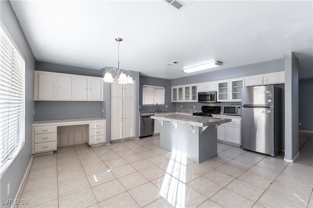 kitchen with white cabinets, light tile patterned floors, a kitchen island, a kitchen bar, and stainless steel appliances