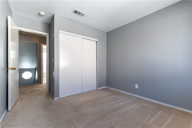 unfurnished bedroom with light carpet and a closet