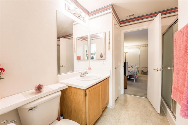 bathroom featuring toilet, vanity, and a shower with door