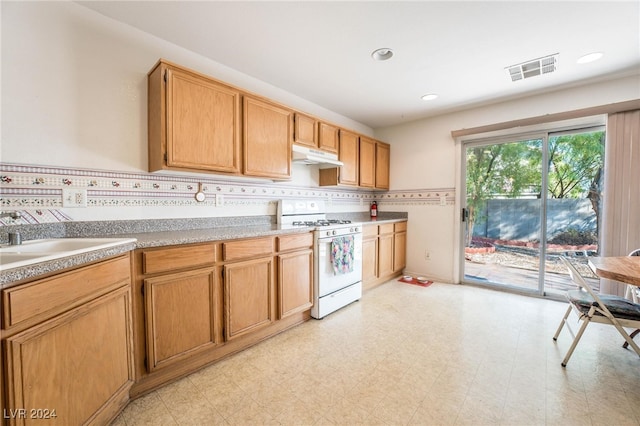 kitchen with white gas stove, sink, and backsplash