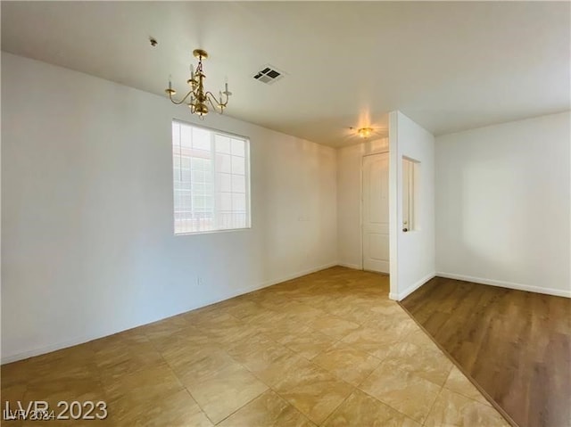 unfurnished room featuring a chandelier and light hardwood / wood-style flooring