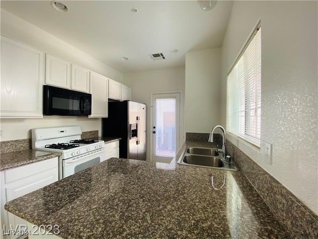 kitchen with stainless steel fridge, sink, white cabinetry, and gas range gas stove