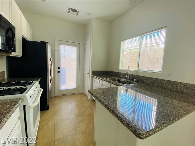 kitchen with white cabinets, a healthy amount of sunlight, white gas range, and sink