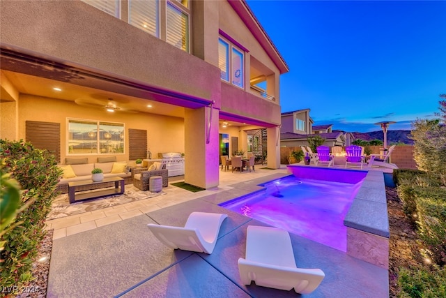 pool at dusk with an outdoor living space, a patio area, and ceiling fan