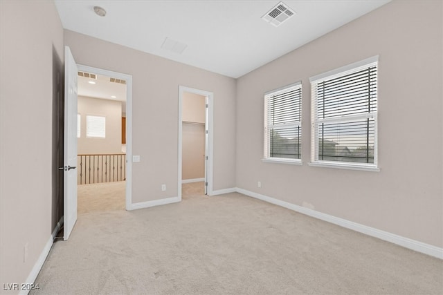 unfurnished bedroom featuring a spacious closet, a closet, and light colored carpet