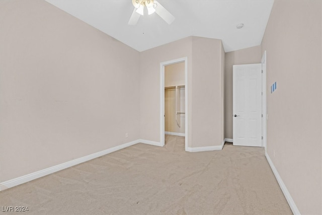 unfurnished bedroom featuring lofted ceiling, a closet, light carpet, a spacious closet, and ceiling fan