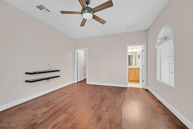 unfurnished bedroom featuring ensuite bathroom, hardwood / wood-style flooring, and ceiling fan