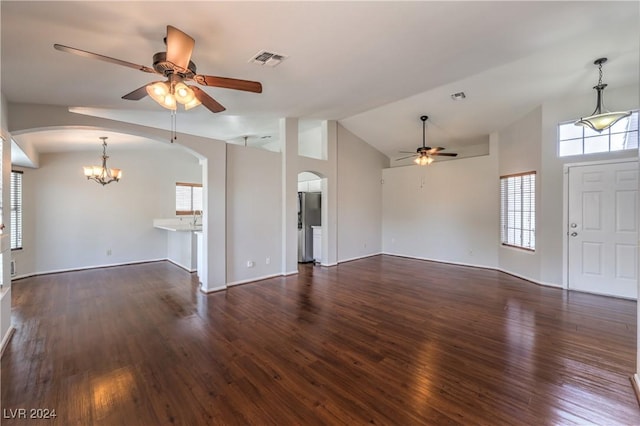 unfurnished living room featuring visible vents, arched walkways, wood finished floors, vaulted ceiling, and ceiling fan with notable chandelier