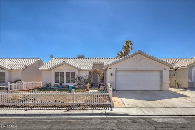 ranch-style house featuring a garage, a fenced front yard, concrete driveway, and stucco siding