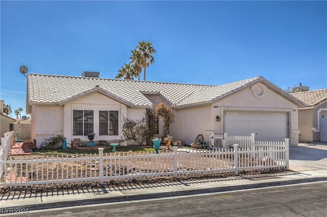 single story home with a fenced front yard, a tile roof, stucco siding, a garage, and driveway