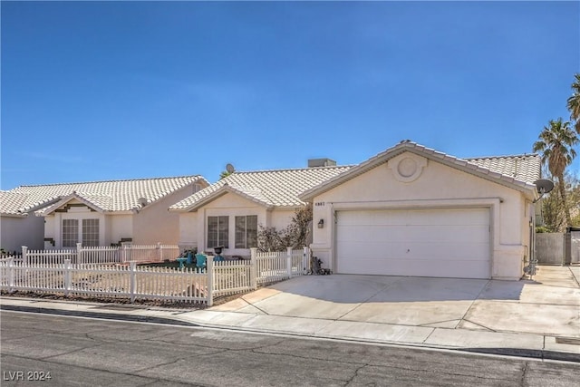 view of front of home featuring a garage, driveway, a fenced front yard, a tile roof, and stucco siding