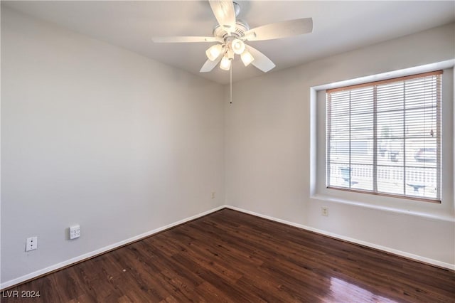 spare room with ceiling fan, dark wood-style flooring, and baseboards