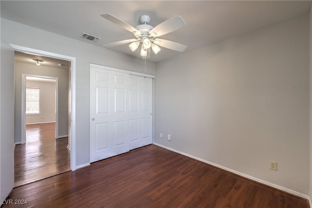 unfurnished bedroom with dark wood-style floors, a closet, visible vents, and baseboards