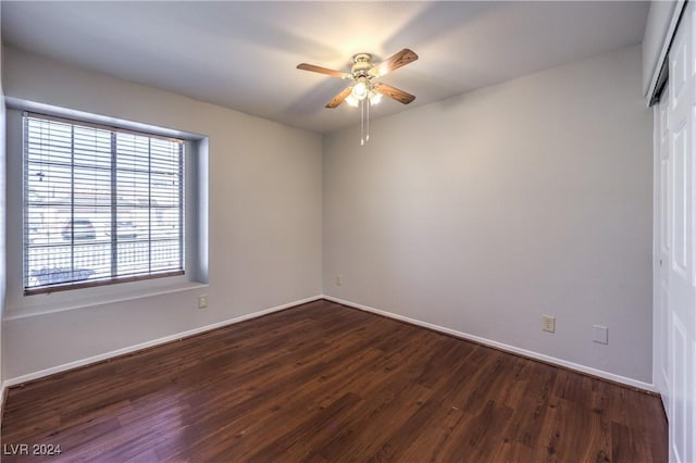 spare room featuring dark wood-style floors, ceiling fan, and baseboards