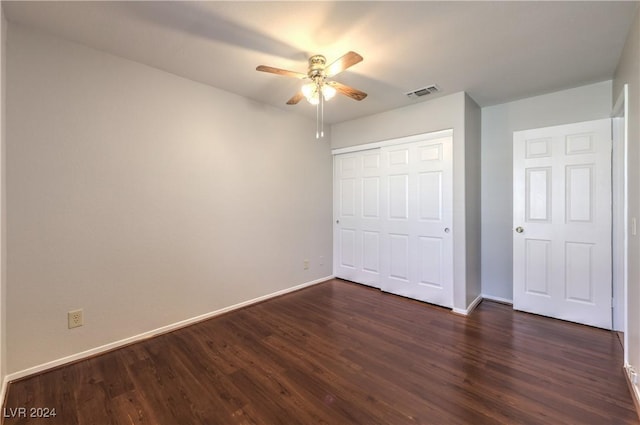 unfurnished bedroom featuring dark wood-type flooring, a closet, visible vents, and baseboards