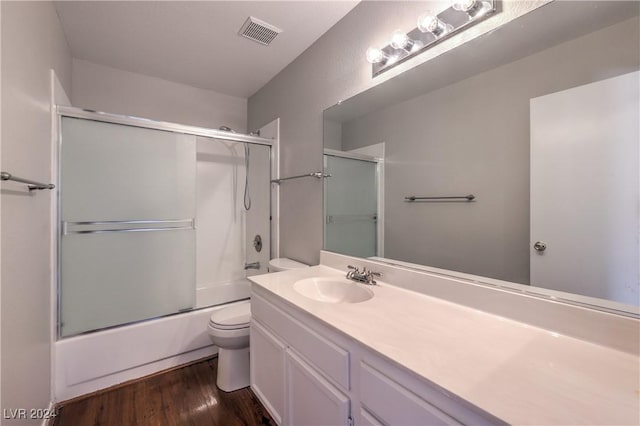 full bath with toilet, wood finished floors, vanity, visible vents, and combined bath / shower with glass door