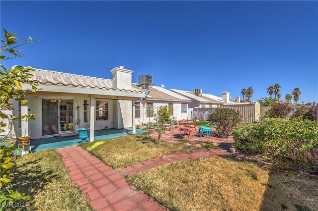 back of house featuring a patio, a chimney, central air condition unit, fence, and a tiled roof