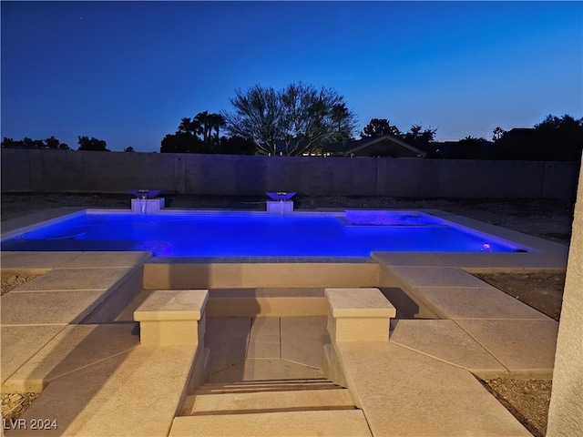 pool at dusk with a hot tub