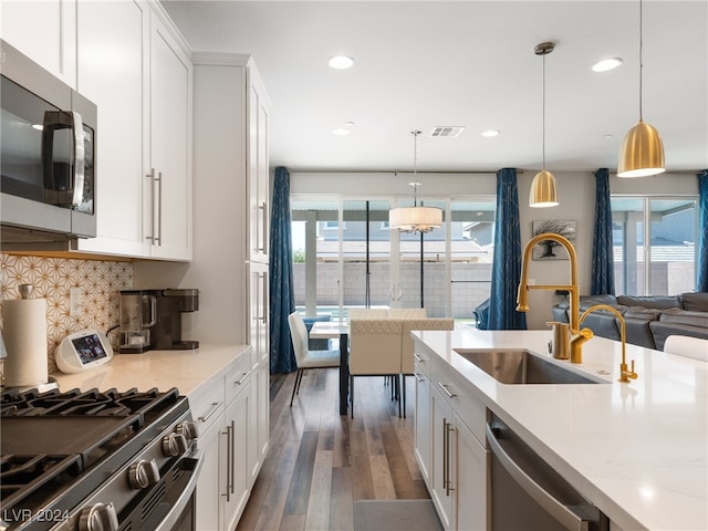 kitchen with stainless steel appliances, sink, dark hardwood / wood-style floors, pendant lighting, and white cabinetry