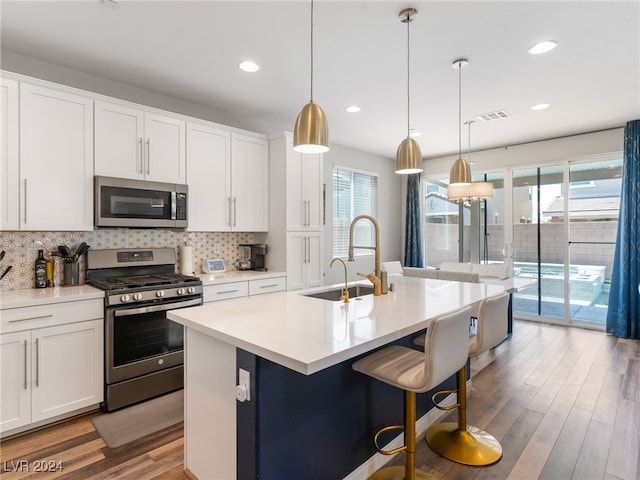 kitchen with appliances with stainless steel finishes, sink, an island with sink, and white cabinets