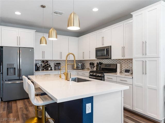 kitchen featuring a center island with sink, appliances with stainless steel finishes, dark hardwood / wood-style floors, decorative light fixtures, and white cabinets