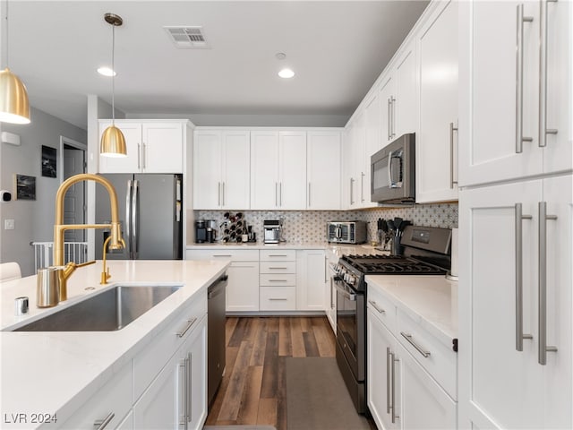 kitchen with white cabinetry, appliances with stainless steel finishes, dark hardwood / wood-style flooring, hanging light fixtures, and sink