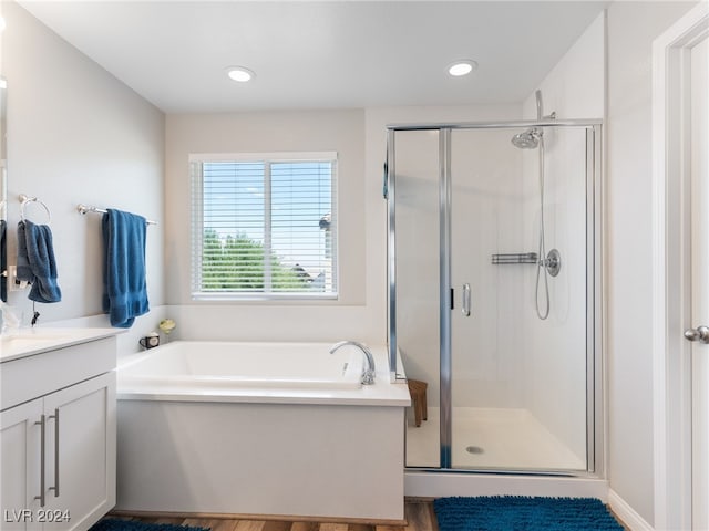 bathroom featuring hardwood / wood-style flooring, vanity, and plus walk in shower