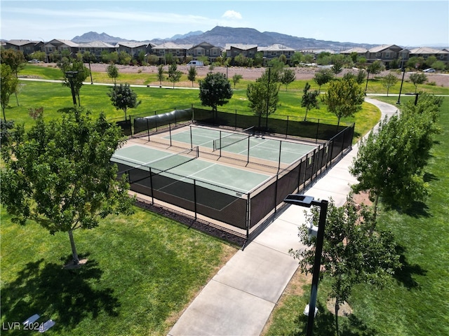 view of tennis court with a mountain view and a lawn