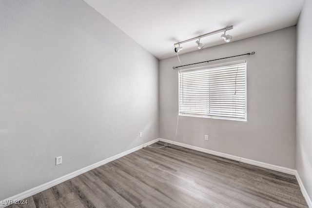 empty room featuring wood-type flooring and track lighting